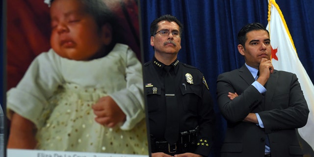 Long Beach Police Chief Robert Luna, left, and Mayor Robert Garcia stand during a news conference in Long Beach, Calif., Wednesday, March 25, 2015. Southern California authorities have arrested four people in a plot to kidnap two newborn babies. The plot ended with the death of a 3-week-old girl and the shooting and beating of the childrenâs mothers, police said Wednesday. At left is an image of baby Eliza Delacruz, who was snatched Jan. 3, 2015, in Long Beach by a gunman who wounded her parents and uncle, Luna said. Her body was found the next day in a trash bin near the Mexican border. (AP Photo/The Daily Breeze, Scott Varley) MAGS OUT; NO SALES