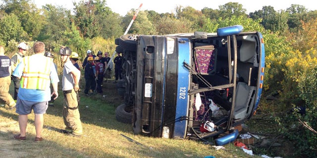 September 21, 2014: Passengers from a tour bus are treated for injuries near the overturned bus at the Tybouts Corner on ramp from southbound Del. 1 to Red Lion Road. (AP Photo/The Wilmington News-Journal, John J. Jankowski)