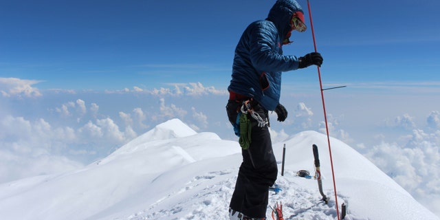 In this June 24, 2015, photo provided by Compass Data/USGS, Blaine Horner of CompassData probes the snow pack at the highest point in North America along with setting up Global Position System equipment for precise summit elevation data on top of Denali in Denali National Park, Ak.