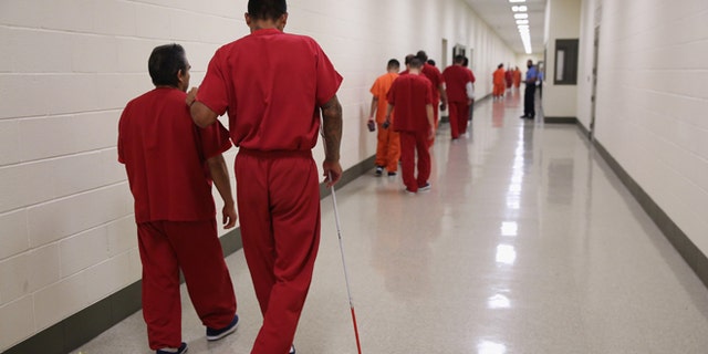 A blind detainee walks with a fellow immigrant at the Adelanto Detention Facility on November 15, 2013 in Adelanto, California. (Photo by John Moore/Getty Images)