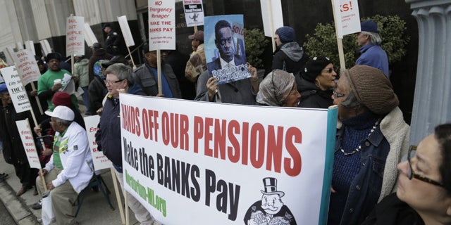 April 1, 2014: Protestors against deeper cuts in pensions march in front of the Theodore Levin Federal Courthouse in Detroit. (AP Photo/Detroit Free Press, Mandi Wright, File)