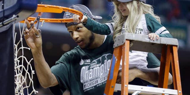 In this March 16, 2014, file photo, Michigan State forward Adreian Payne, left, cuts the net with Lacey Holsworth. Holsworth died in April 2014, after a battle with nerve-cell cancer. (AP Photo/Michael Conroy, File)