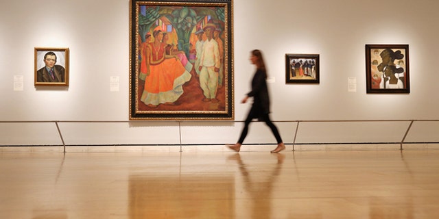LONDON, ENGLAND - JULY 02: A woman walks past a painting by Diego Rivera entitled 'Dance in Tehuantepec' (C) in the Royal Academy of Arts on July 2, 2013 in London, England. The painting features in the exhibition 'Mexico: A Revolution in Art, 1910-1940' which examines artworks influenced by the period of revolution and turmoil in Mexico between 1910 and 1920. The exhibition, which showcases 120 paintings and photographs, open to the public on July 6, 2013 and runs until September 29, 2013. (Photo by Oli Scarff/Getty Images)