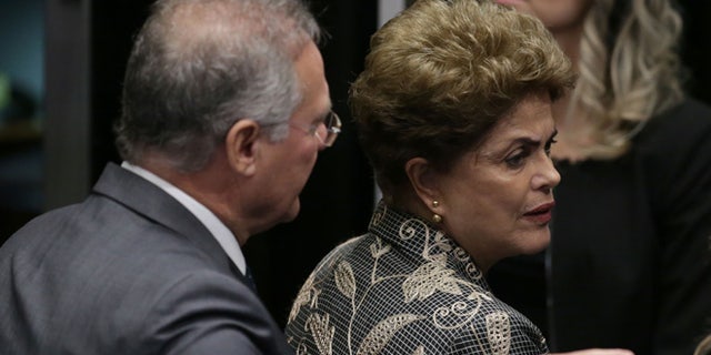 Brazil's Senate leader Renan Calheiros points to an exit as suspended President Dilma Rousseff looks to leave Senate chambers after addressing the lawmakers, at the start of a short recess of her own impeachment trial, in Brasilia, Brazil, Monday, Aug. 29, 2016. Fighting to save her job, Rousseff told senators on Monday that the allegations against her have no merit. "I know I will be judged, but my conscience is clear. I did not commit a crime," she told senators. Rousseff's address comes on the fourth day of the trial. (AP Photo/Eraldo Peres)