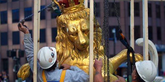 In this Sept. 14, 2014 file photo, a lion statue is removed from atop the Old State House on Washington Street in Boston.