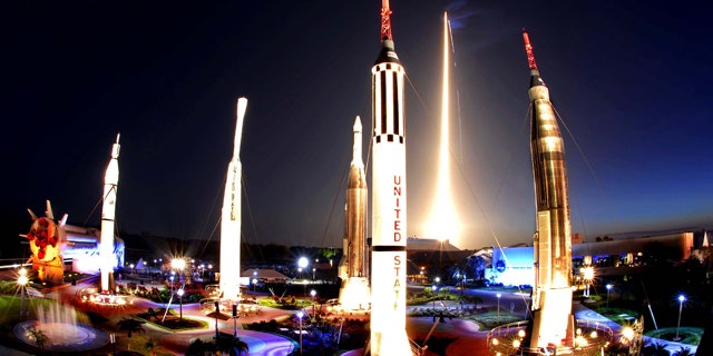 The Space Shuttle Discovery lights up the sky, seen at rear top, at the Rocket Garden at Kennedy Space Center visitor complex during a predawn liftoff early Monday morning, April 5, 2010, from pad 39a at the Kennedy Space Center on course for a mission to the International Space Station.