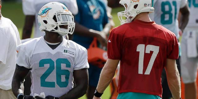 Miami Dolphins running back Lamar Miller (26) talks to quarterback Ryan Tannehill (17) during NFL football training camp in Davie, Fla., Wednesday, July 30, 2014. (AP Photo/Alan Diaz)