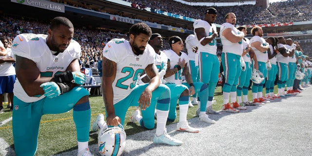 Dolphins players Jelani Jenkins, Arian Foster, Michael Thomas, and Kenny Stills kneeling during the national anthem on Sept. 11, 2016, in Seattle.