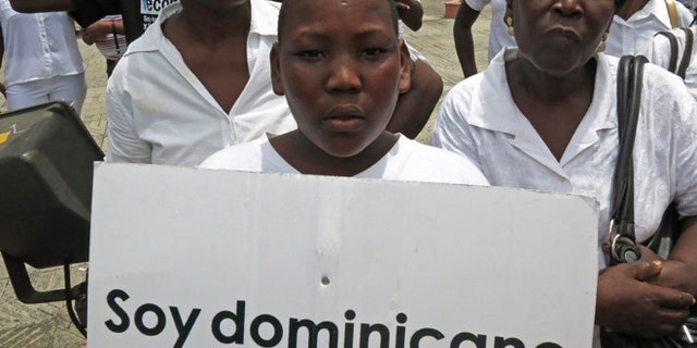 FILE - In this Aug. 12, 2013 file photo, a youth of Haitian descent holds a sign that reads in Spanish "I'm Dominican" during a protest demanding that President Danilo Medina stop the process to invalidate their birth certificates after authorities retained their ID cards, in Santo Domingo, Dominican Republic. The Dominican Republic's top court on Thursday, Sept. 26, 2013 stripped citizenship from thousands of people born to migrants who came illegally, a category that overwhelmingly includes Haitians brought in to work on farms. The decision cannot be appealed, and it affects all those born since 1929. (AP Photo/Ezequiel Abiu Lopez, File)