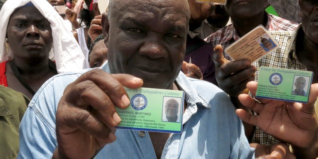 Haitian Jaquenol Martinez shows a card that proves that he has worked in the Dominican sugar cane fields since 1963, while trying to apply for a temporary resident permit, in Santo Domingo, Dominican Republic, Monday, June 15, 2015. Hundreds of Haitians are waiting in long lines throughout the Dominican Republic trying to secure legal residency as they face the threat of deportation. The government has given non-citizens until Tuesday to register under an initiative aimed at regulating the flow of migrants from neighboring Haiti. (AP Photo/Ezequiel Abiu Lopez)