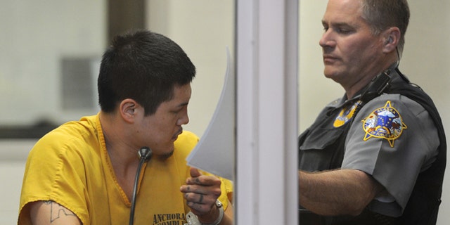 May 26, 2013: An officer in the Anchorage jail court removes the paperwork that Jerry Andrew Active was using to shield his face during his arraigned on charges of murder and sexual assault of a minor in Anchorage, Alaska.