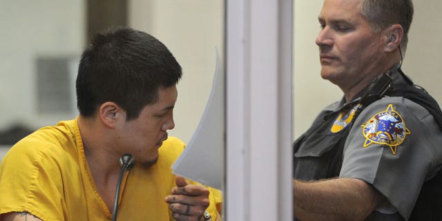 May 26, 2013: An officer in the Anchorage jail court removes the paperwork that Jerry Andrew Active was using to shield his face during his arraigned on charges of murder and sexual assault of a minor.