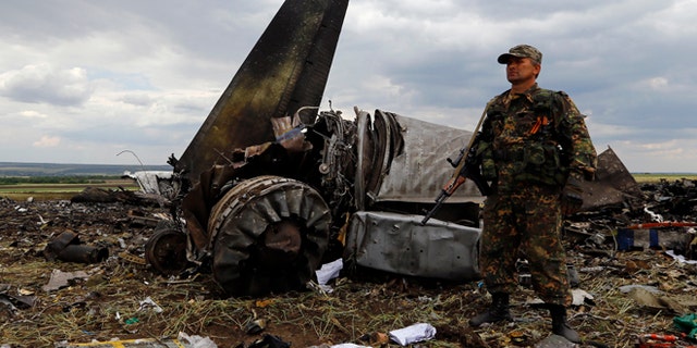 June 14: An armed pro-Russian separatist stands guard at the site of the crash of the Il-76 Ukrainian army transport plane in Luhansk.