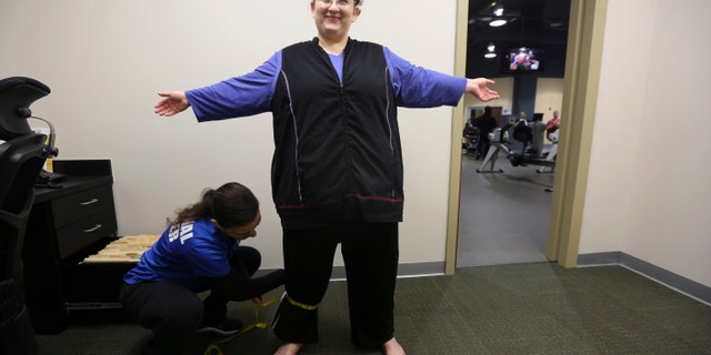 Personal trainer Krisaane Hale, bottom, measures Ellen Hays for body mass index reading before working out in a morning exercise class at the Downsize Fitness gym in Addison, Texas.