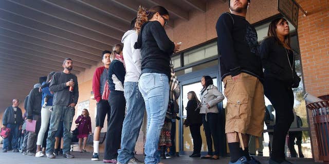 FILE - This Dec. 22, 2014 file photo a line stretches outside an a Arizona Department of Transportation Motor Vehicle Division office, begin pursuing Arizona driver's licenses. Only a small number of young immigrants who qualify for Arizona driver's licenses after a judge overturned a state ban have actually obtained licenses. Immigrant advocates say not enough people know they qualify. (AP Photo/Ross D. Franklin,File)