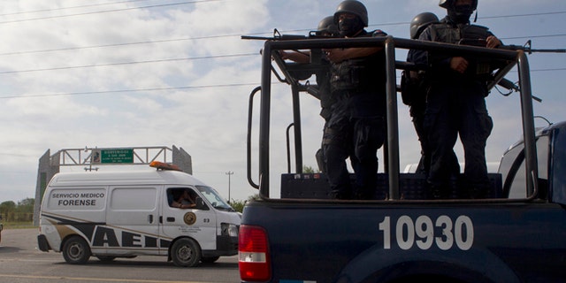 Federal police on a vehicle guard one of the three forensic trucks where several bodies were placed after dozens of bodies, some of them mutilated, were found on a highway connecting the northern Mexican metropolis of Monterrey to the U.S. border found in the Km 47 of the Reynosa-Cadereyta road in the town of San Juan near the city of Monterrey, Mexico, Sunday, May 13, 2012. (AP Photo/Christian Palma)