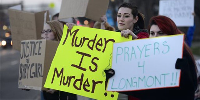 Renee Jacoby, at center, holds a sign with others during a protest against Dynel Lane on Thursday, March 19, 2015, in Longmont, Colo. Lane is accused of stabbing a pregnant woman in the stomach and removing her baby, while the expectant mother visited her home to buy baby clothes advertised on Craigslist authorities said. The baby did not survive. (AP Photo/The Daily Camera, Jeremy Papasso) NO SALES