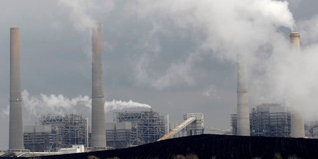 FILE - In this March 16, 2011, file photo, exhaust rises from smokestacks in front of piles of coal in Thompsons, Texas. (AP Photo/David J. Phillip, File)