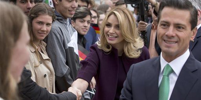 In this April 11, 2016 file photo, Mexico's President Enrique Pena Nieto, right, and his wife Angelica Rivera de Pena greet students as they arrive to meet with Germany's President Joachim Gauck at Bellevue Palace in Berlin, Germany. Pena Nieto apologized on Monday, July 18, 2016 for a 2014 scandal involving a mansion his wife bought from a firm that won lucrative contracts with his administration. (AP Photo/Michael Sohn, File)