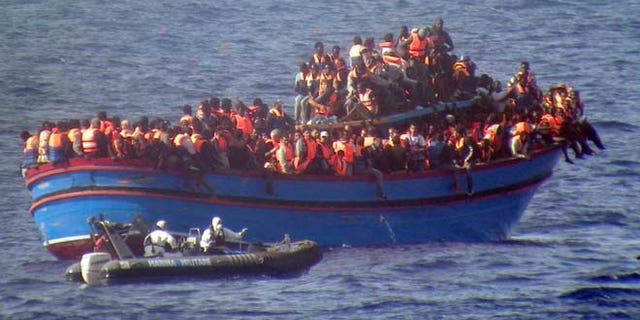 FILE - In this June 29, 2014 file photo released by the Italian Navy a motor boat from the Italian frigate Grecale approaches a boat overcrowded with migrants in the Mediterranean Sea. The bodies of some 30 would-be migrants were found in in the hold of a packed smugglers' boat that was carrying nearly 600 people making its way to Italy. (AP Photo/Italian Navy, ho)