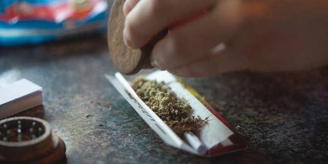 In this photo taken Friday, Dec. 20, 2013, a visitor rolls a marijuana joint in coffee shop Mississippi in Maastricht, southern Netherlands. While several U.S. states have moved to legalize the sale of marijuana, the Netherlands is going in the opposite direction, clamping down on its famed tolerance policy toward weed. In Maastricht, attempts to ban foreigners from buying weed have led to a resurgence of street-dealers, while Amsterdam is shutting marijuana cafes located too close to schools. (AP Photo/Ermindo Armino)