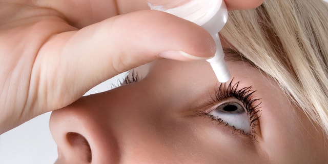 woman applying eyedroppes, close up