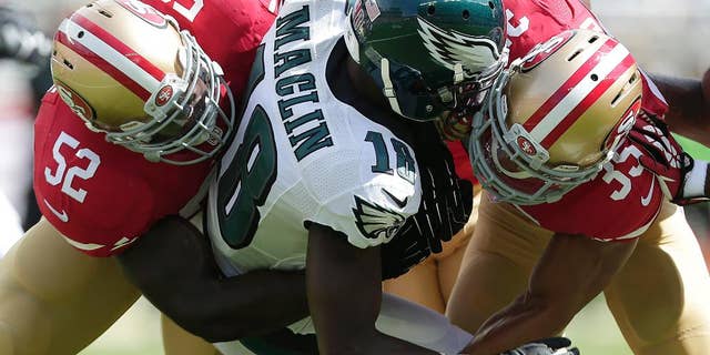 Philadelphia Eagles wide receiver Jeremy Maclin (18) is tackled by San Francisco 49ers linebacker Patrick Willis (52) and safety Eric Reid (35) during the first quarter of an NFL football game in Santa Clara, Calif., Sunday, Sept. 28, 2014. (AP Photo/Marcio Jose Sanchez)