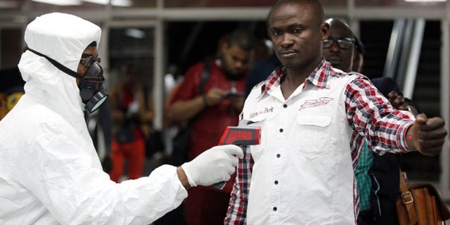 In this Aug. 6, 2014 file photo, a Nigerian port health official uses a thermometer on a worker at the arrivals hall of Murtala Muhammed International Airport in Lagos, Nigeria.
