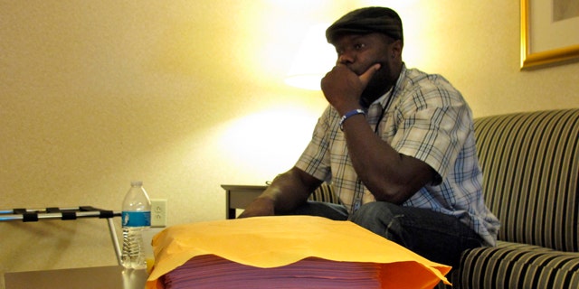 October 10, 2014: Josephus Weeks, nephew of Ebola patient Thomas Eric Duncan who died earlier this week in Dallas, sits behind a stack of medical documents in a hotel room in Kannapolis, N.C. (AP Photo/Allen G. Breed)
