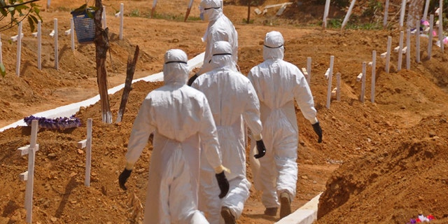 FILE- In this file photo dated Wednesday, March 11, 2015, health workers walk inside a new graveyard for Ebola victims, on the outskirts of Monrovia, Liberia. Despite the drop in reported Ebola cases, Dr. Bruce Aylward, leading WHOs Ebola response, declared Friday April 10, 2015, that its too early for World Health Organization to downgrade the global emergency status of the biggest-ever Ebola outbreak in Africa. (AP Photo/Abbas Dulleh, FILE)