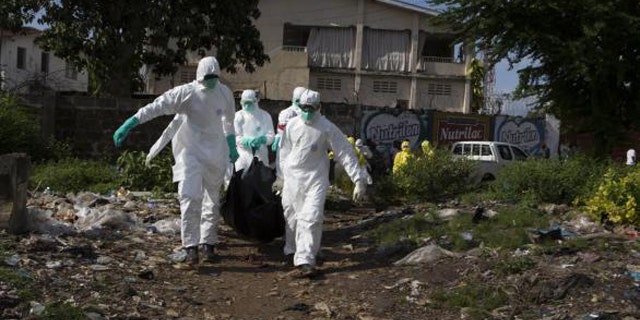 September 28, 2014: A burial team wearing protective clothing remove a body of a person suspected of having died of the Ebola virus in Freetown, Sierra Leone (REUTERS/Christopher Black/WHO/Handout via Reuters)