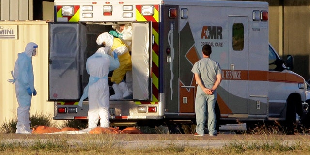 Medical staff in protective gear escort Nina Pham, exiting the ambulance, to a nearby aircraft at Love Field, Thursday, Oct. 16, 2014, in Dallas, Texas.