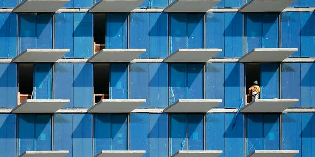 In this Tuesday, Feb. 3, 2015 photo, a construction worker stands on an outside balcony at Brickell City Centre, a $1.05 billion mixed-use development is located in Miami's financial district. The Commerce Department issues its second of three estimates of how fast the U.S. economy grew in the October-December quarter on Friday, Feb. 27, 2015. (AP Photo/Lynne Sladky)
