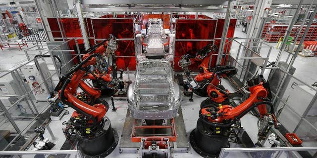 In this May 14, 2015 photo, Kuka robots work on Tesla Model S cars in the Tesla factory in Fremont, Calif. The Institute for Supply Management, a trade group of purchasing managers, issues its index of manufacturing activity for May on Monday, June 1, 2015. (AP Photo/Jeff Chiu)