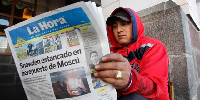 A man reads a newspaper with the headline in Spanish "Snowden stuck at Moscow airport" in Quito, Ecuador, June 26, 2013.