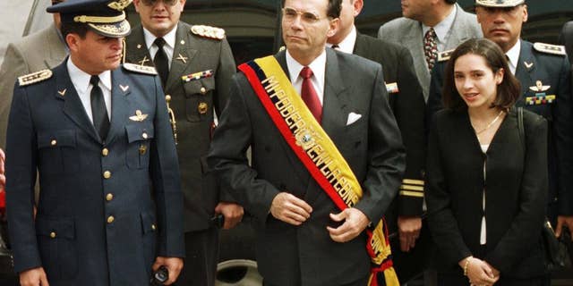 FILE - In this Jan. 15, 2000 file photo, Ecuador's President Jamil Mahuad, center, his daughter Paola Mahuad, right, and military officials arrive to Congress in Quito, Ecuador. Ecuadorean authorities announced on Tuesday, May 27, 2014 via Twitter that an arrest warrant has been issued for former President Jamil Mahuad for allegedly misappropriating public funds during the country's late 1990s banking crisis. Mahuad fled a 2000 coup and settled in the United States. (AP Photo/Silvia Izquierdo, File)