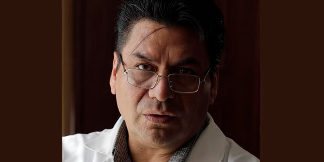 Dr. Carlos Figueroa holds his cell phone as he gives an interview in Quito, Ecuador, on Aug. 3, 2015.