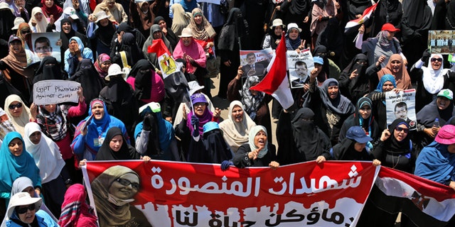 July 21, 2013: Supporters of ousted Egyptian President Mohammed Morsi carry a banner with Arabic words that reads, "Martyrs of Mansoura, your bloods is life for us," depicting a woman who was killed during a recent protest, as they attend a demonstration in front of the National Council for Human Right building in Cairo, Egypt.
