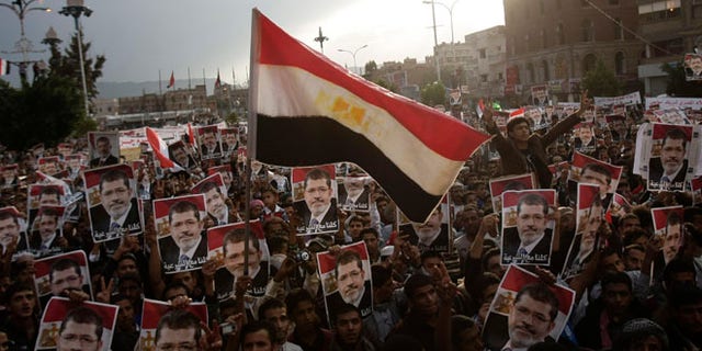 Aug 15, 2013: Yemeni protesters wave an Egyptian flag as they hold posters of Egypt's ousted President Mohammed Morsi during a rally supporting Morsi in Sanaa, Yemen.