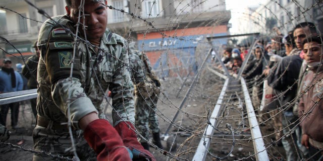 Nov. 24, 2011: An Egyptian soldier helps to put a barbed wire barricade in place, near Tahrir square in Cairo, Egypt.