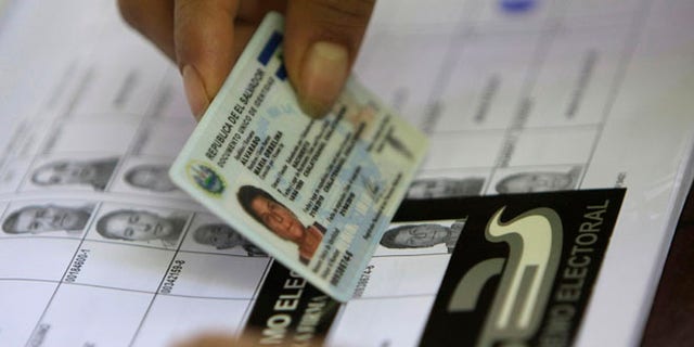 An election worker helps a voter find her name on a voter list during legislative and municipal elections in Suchitoto, El Salvador, Sunday March 11, 2012. (AP Photo/Luis Romero)