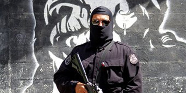 In this April 5, 2016 photo, a masked and armed policeman patrols a gang controlled neighborhood in San Salvador, El Salvador. Hyper-violent gangs declared open-season on police in this Central American nation in response to a government crackdown that began last year. In just three weeks in January, gang members were blamed in the slayings of a cop's father, a soldier's brother, the wives of two police officers and a woman and her son who were relatives of a cop. (AP Photo/Alex Peña)