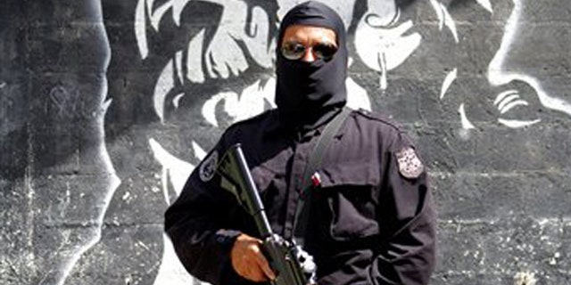 In this April 5, 2016 photo, a masked and armed policeman patrols a gang controlled neighborhood in San Salvador, El Salvador. Hyper-violent gangs declared open-season on police in this Central American nation in response to a government crackdown that began last year. In just three weeks in January, gang members were blamed in the slayings of a cop's father, a soldier's brother, the wives of two police officers and a woman and her son who were relatives of a cop. (AP Photo/Alex Peña)