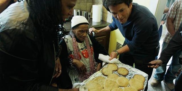 April 4: Detroit Free Press columnist Mitch Albom, right, helps Texana Hollis pull cookies from the oven in her home in Detroit.