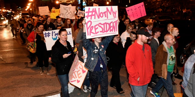 Protesters holds up signs in opposition of Donald Trump's presidential election victory as they march from Jefferson Square Park, Thursday, Nov. 10, 2016 in Louisville Ky. (AP Photo/Timothy D. Easley)