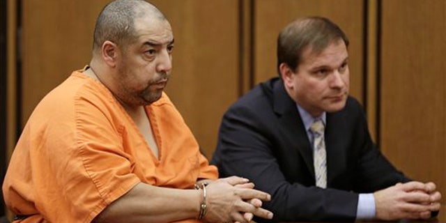Elias Acevedo, left, looks toward the judge during his pretrial hearing Monday, Dec. 2, 2013, in Cleveland. Acevedo, a convicted sex offender, is charged with two murders and 173 counts of rape. The judge set the trial date for Feb. 24, 2014. Defense attorney Bret Jordan, right, listens. (AP Photo/Tony Dejak)