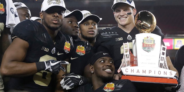 Purdue quarterback Elijah Sindelar, top right, holds the trophy next to teammates after their 38-35 win over Arizona during the Foster Farms Bowl NCAA college football game Wednesday, Dec. 27, 2017, in Santa Clara, Calif. (AP Photo/Marcio Jose Sanchez)