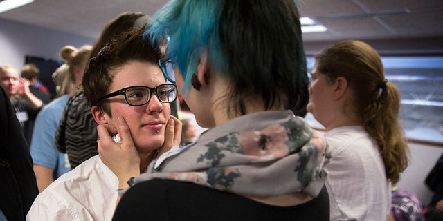 In this Dec. 4, 2014 file photo, Elliott Kunerth, 17, a transgender male high school student hugs his girlfriend, Kelsi Pettit, 17, after the Minnesota State High School League board voted to pass the Model Gender Identity Participation in MSHSL Activities Policy in Brooklyn Park, Minn. (Leila Navidi/Star Tribune via AP)