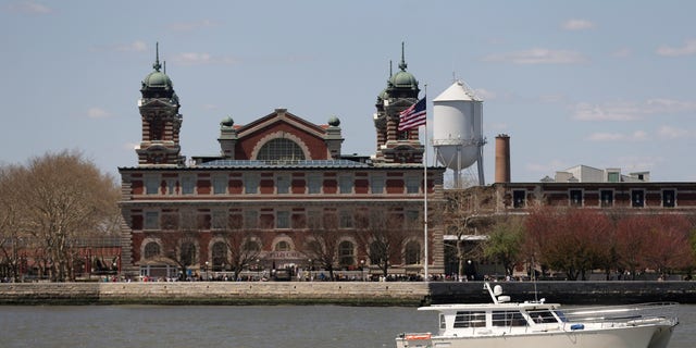 A yacht passes by Ellis Island as it makes its way through New York Harbor.