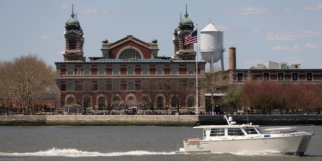 A yacht passes by Ellis Island as it makes its way through New York Harbor.